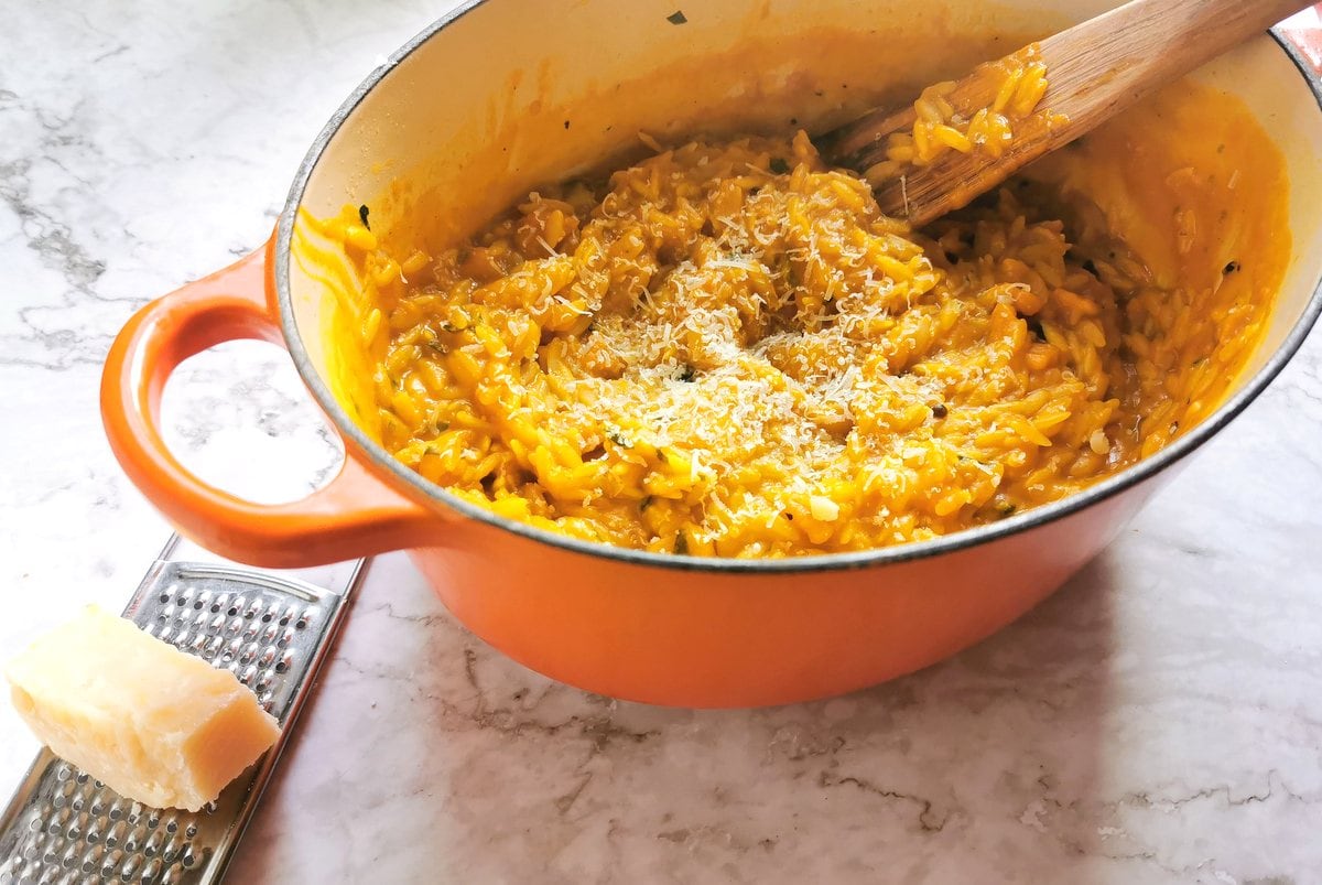 Ready pasta risotto in Dutch oven with grated Parmigiano sprinkled on top.