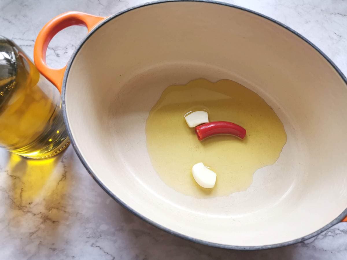 Peeled garlic cloves and half a peperoncino in aDutch oven with olive oil.