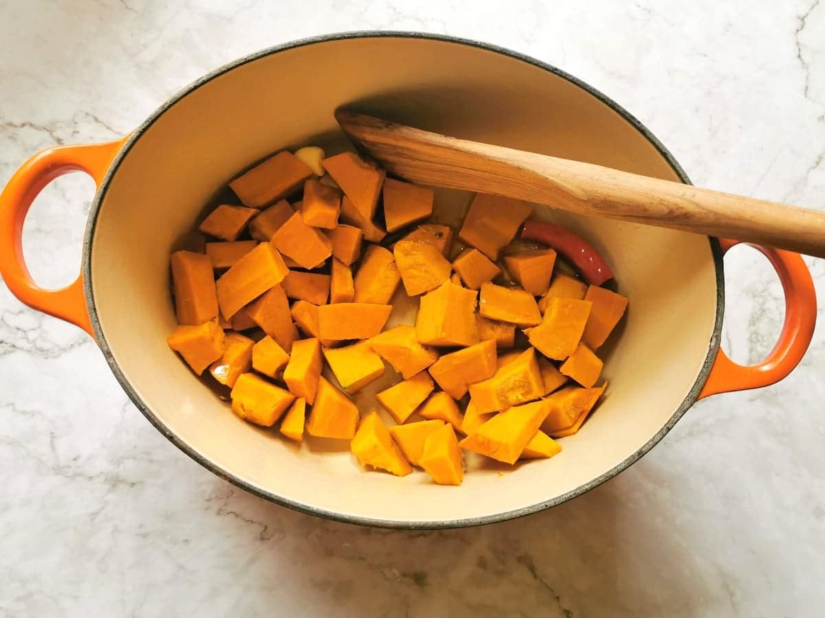 Cubes of pumpkin in a Dutch oven with garlic and peperoncino.