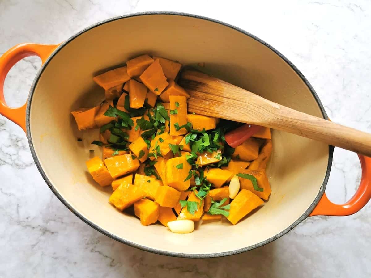 Chopped parsley added to the Dutch oven with pumpkin cubes.