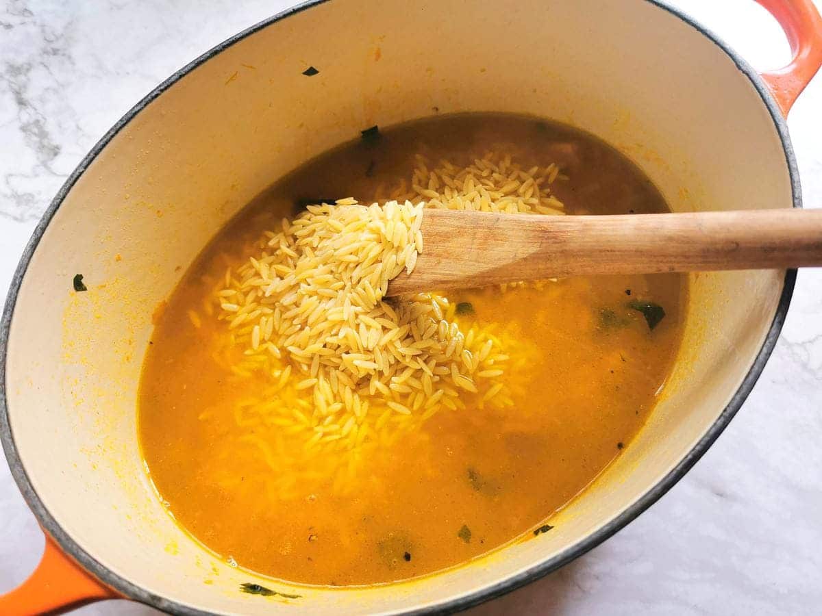 Orzo/risoni pasta added to Dutch oven with vegetable stock.