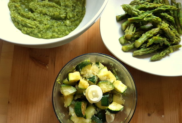 zucchini in blender bowl with asparagus spears and creamed asparagus in white bowls