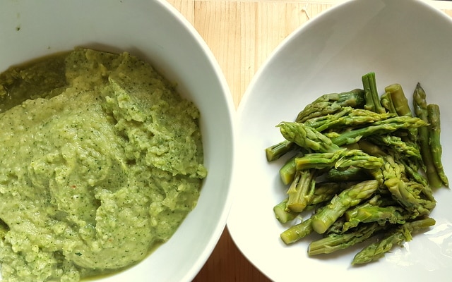 creamed asparagus pasta sauce in white bowl and asparagus spears in white bowl