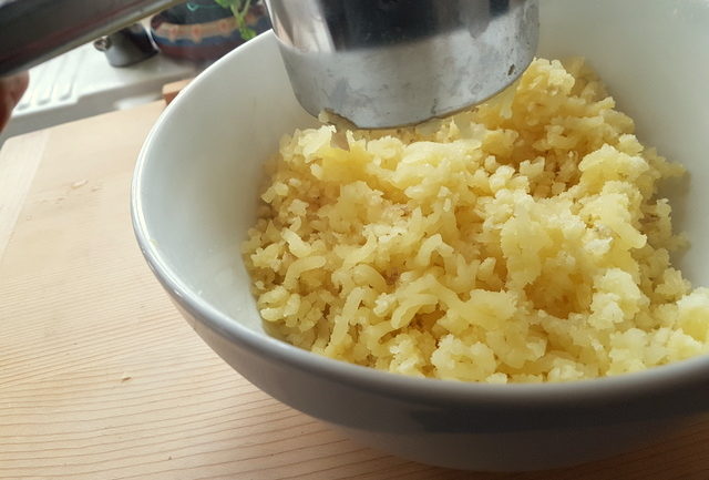 passing cooked potatoes through a potato ricer