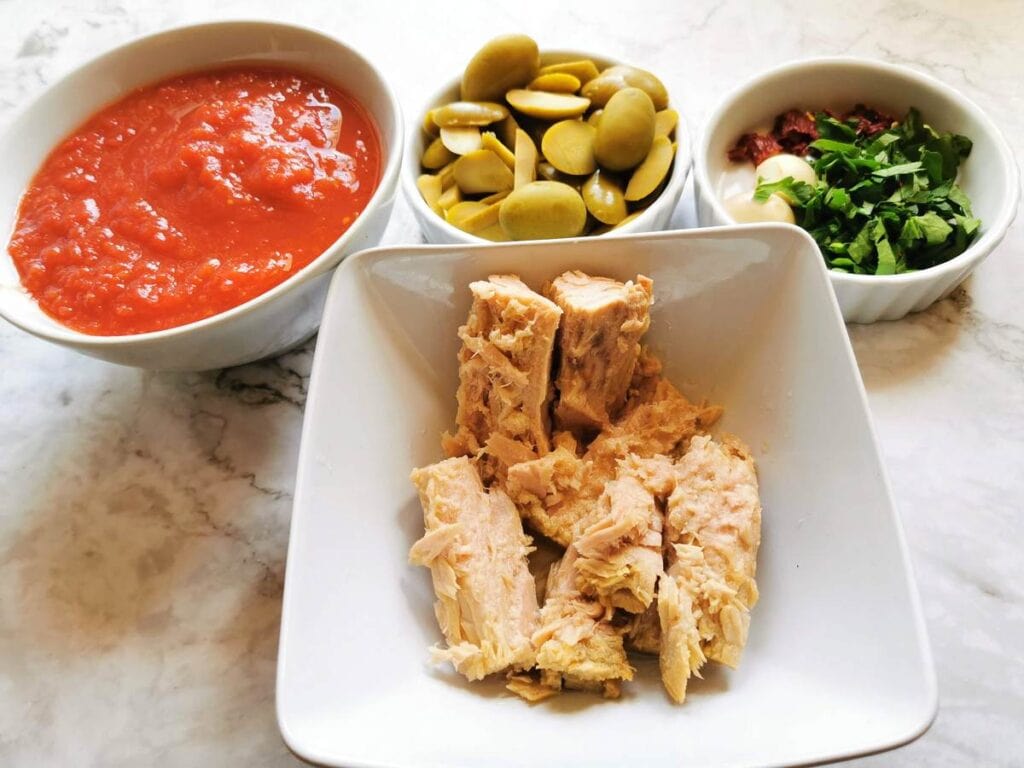 drained tuna,, chopped parsley, peeled garlic, chopped peperoncino, passata and chopeed olives in white bowls