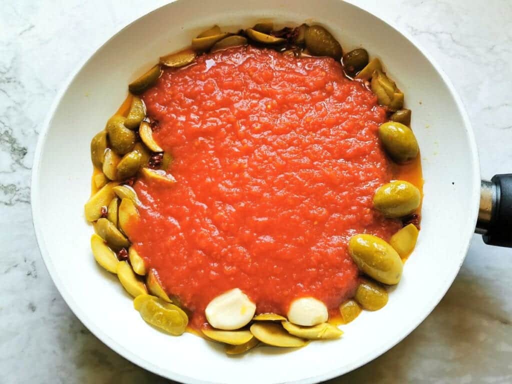 tomato passata added to the pan with olives, garlic and peperoncino