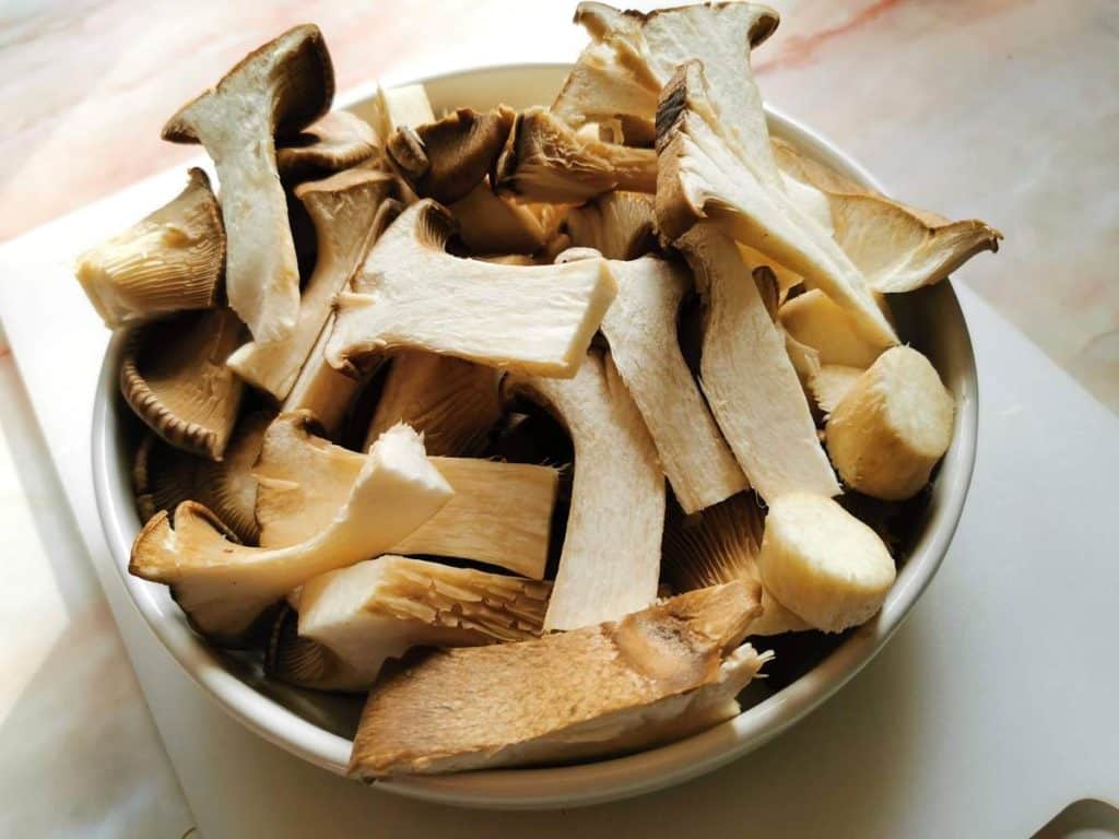 King oyster mushrooms ready cut in white bowl.