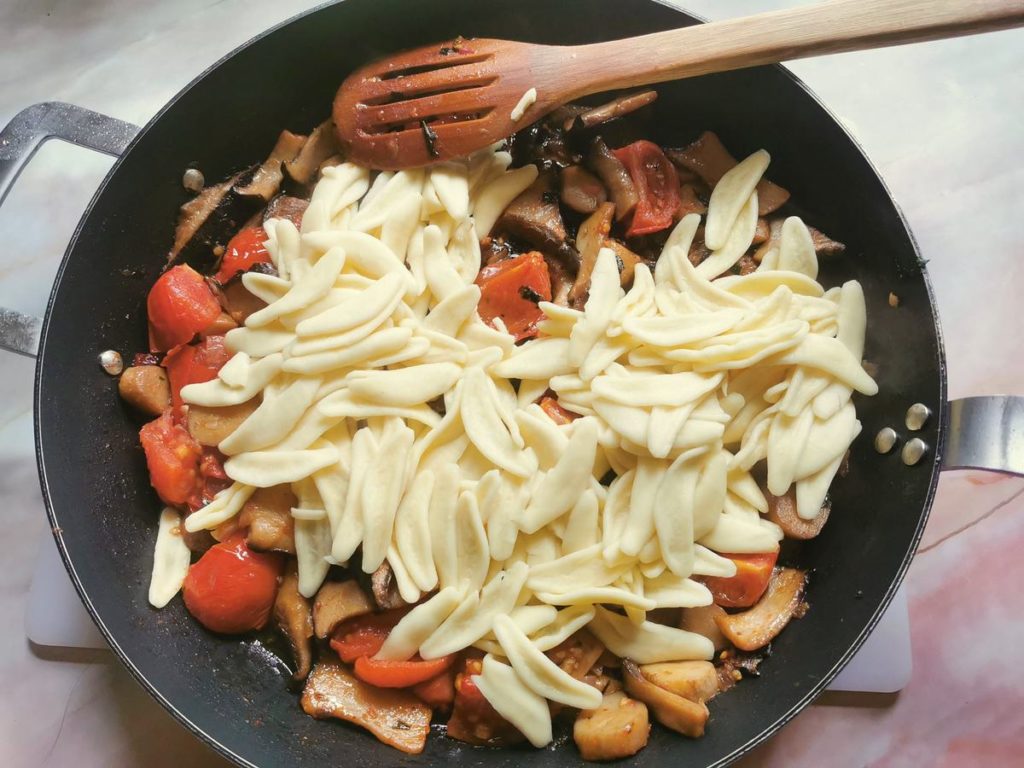 Cooked olive leaf pasta in skillet with king oyster mushroom sauce.