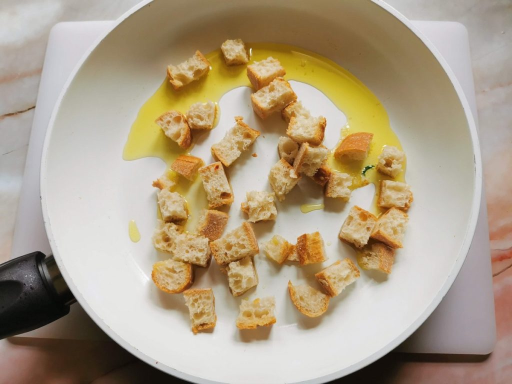 stale bread croutons in frying pan with olive oil.