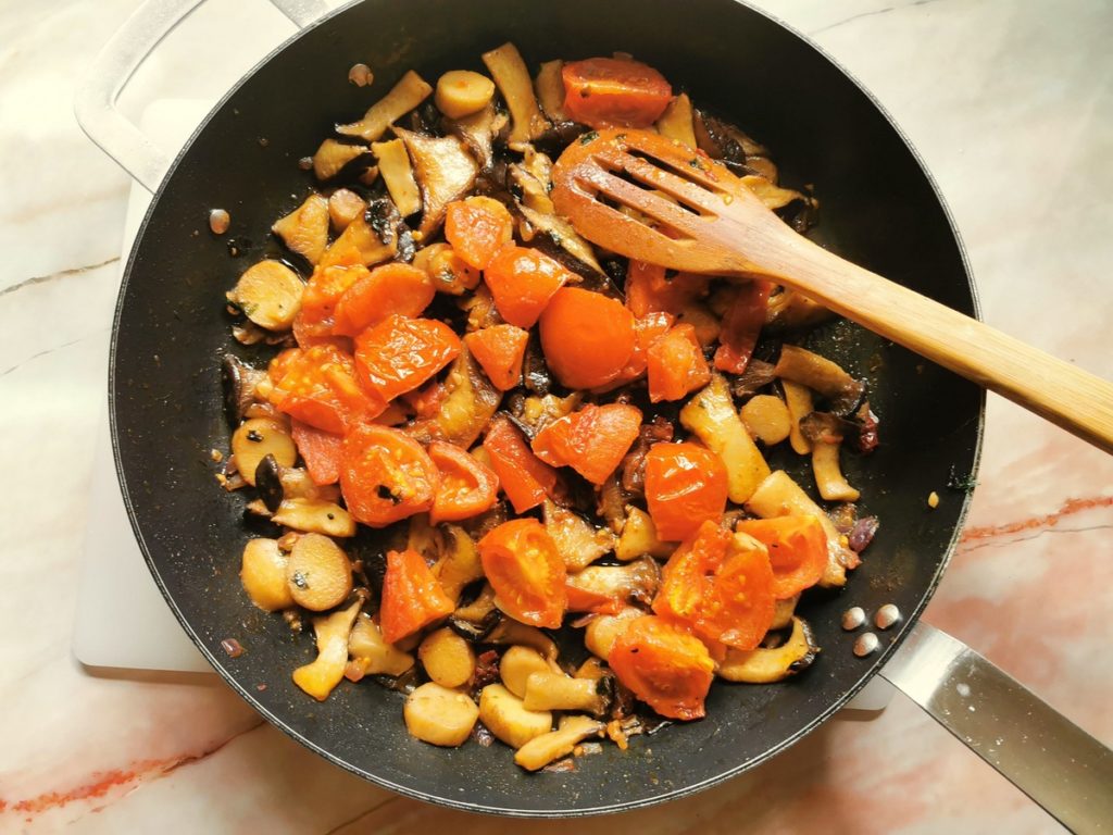 Sautéed tomatoes in skillet with mushrooms.