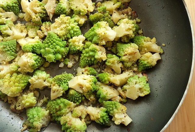 Romanesco broccoli florets cooking in frying pan