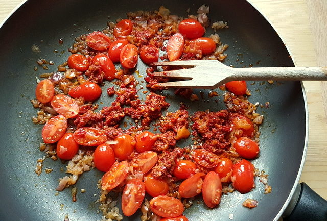 tomatoes, onions and nduja cooking in frying pan