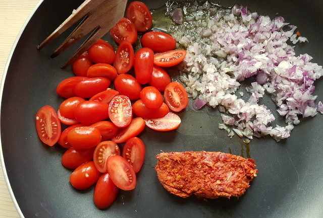 uncooked cherry tomatoes, onions and nduja in frying pan