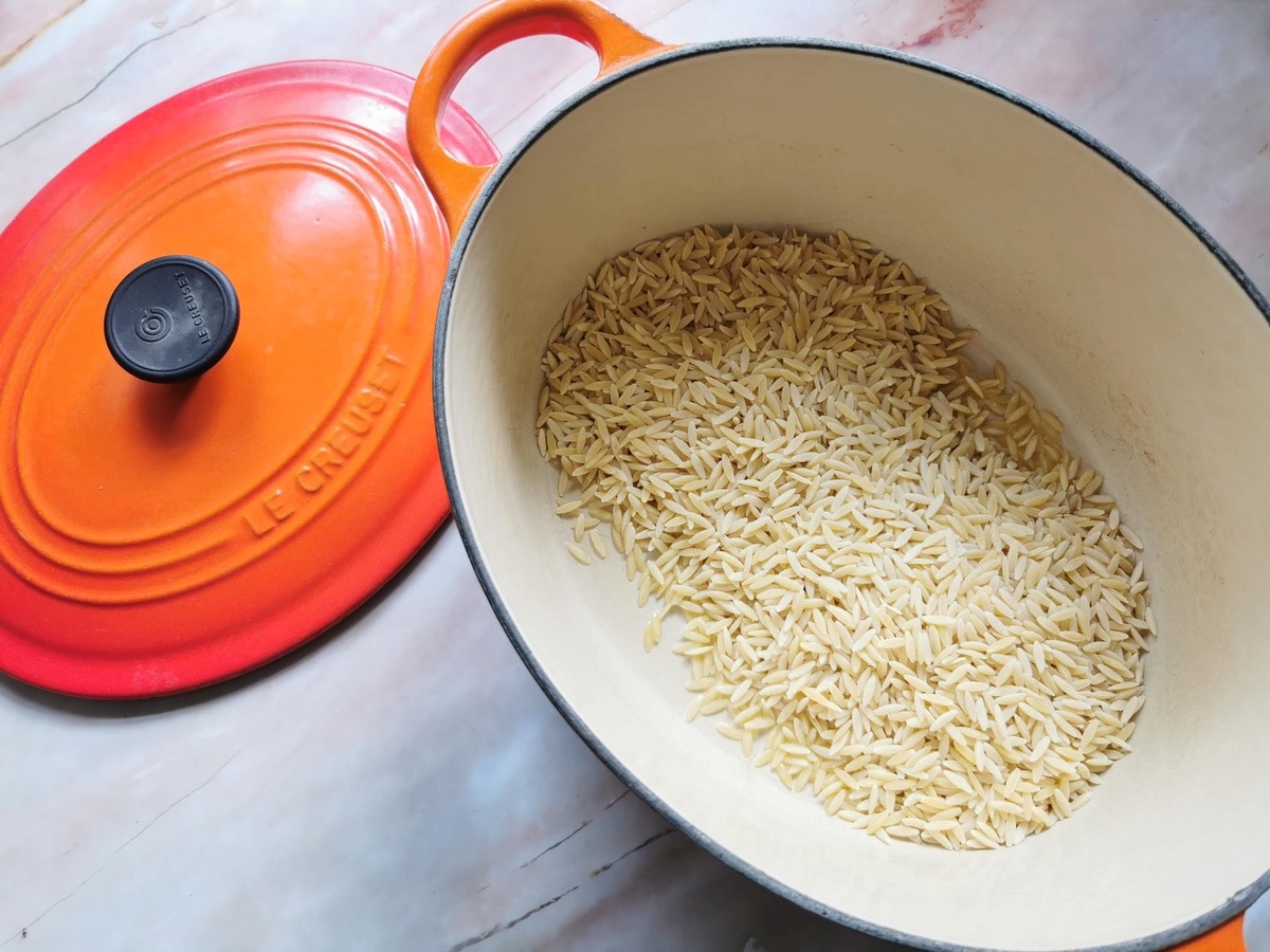 Orzo pasta in Dutch oven with olive oil.