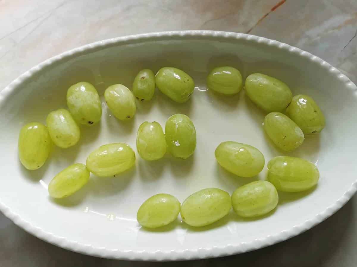 Green grapes in a white oval oven dish.