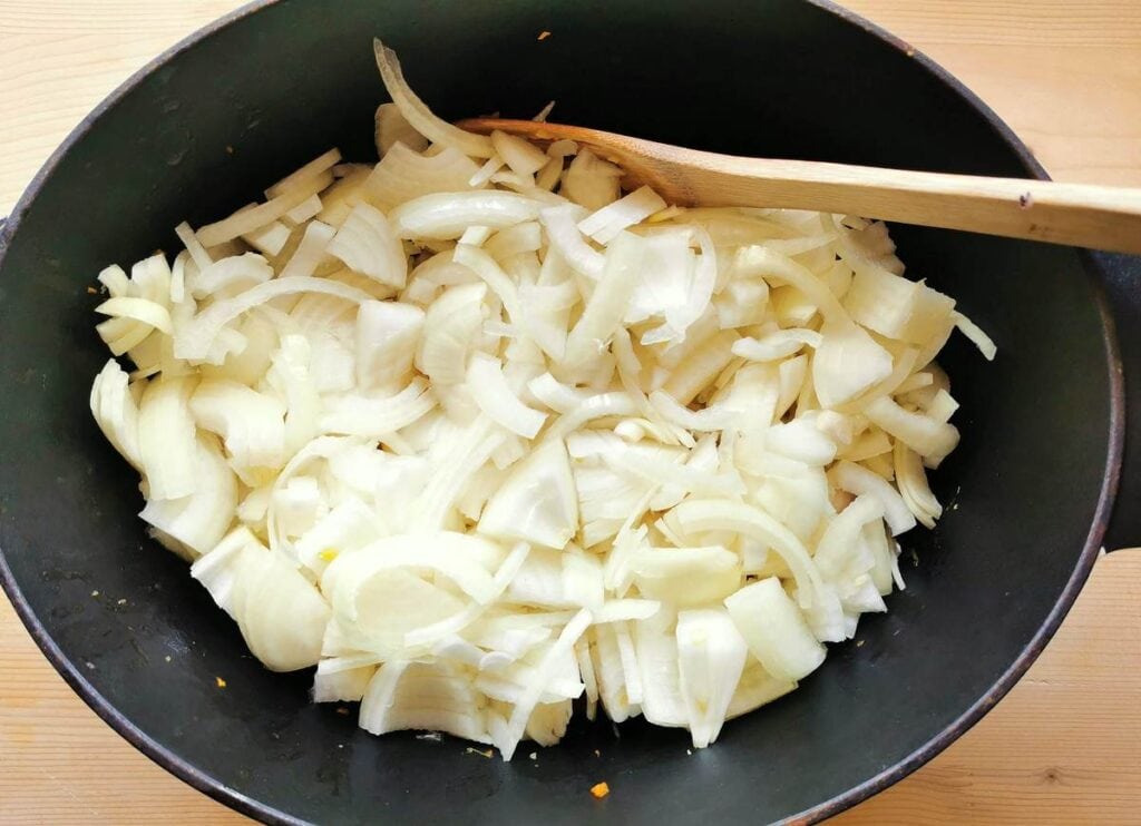 sliced onions in Dutch oven on top of octopus and veggies.