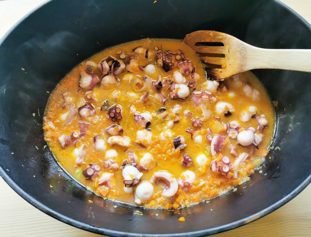 Octopus, celery and carrots cooking in wine in Dutch oven