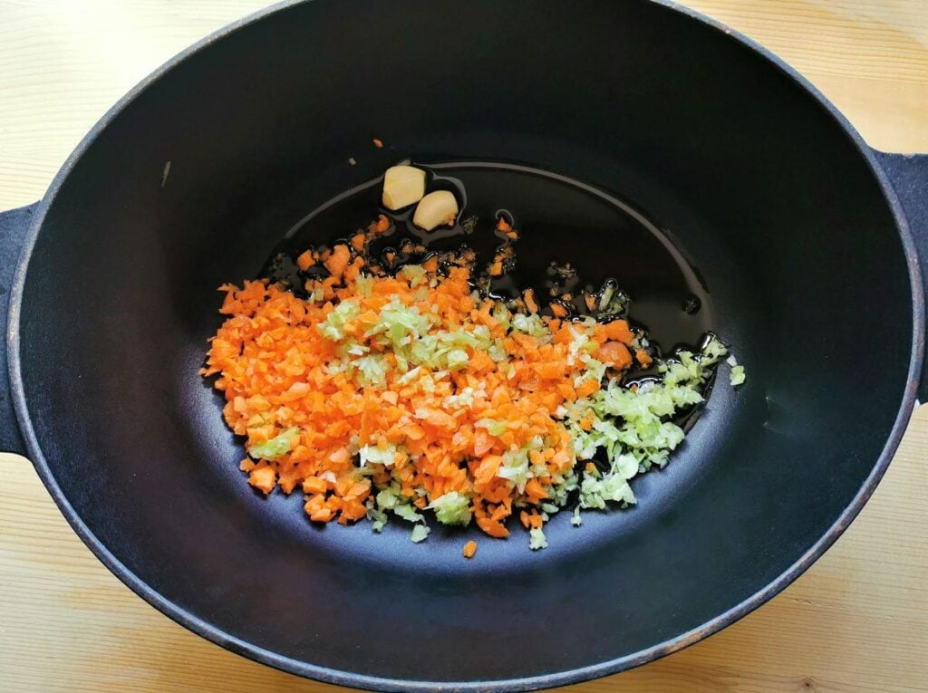 chopped celery and carrots with garlic cloves in Dutch oven