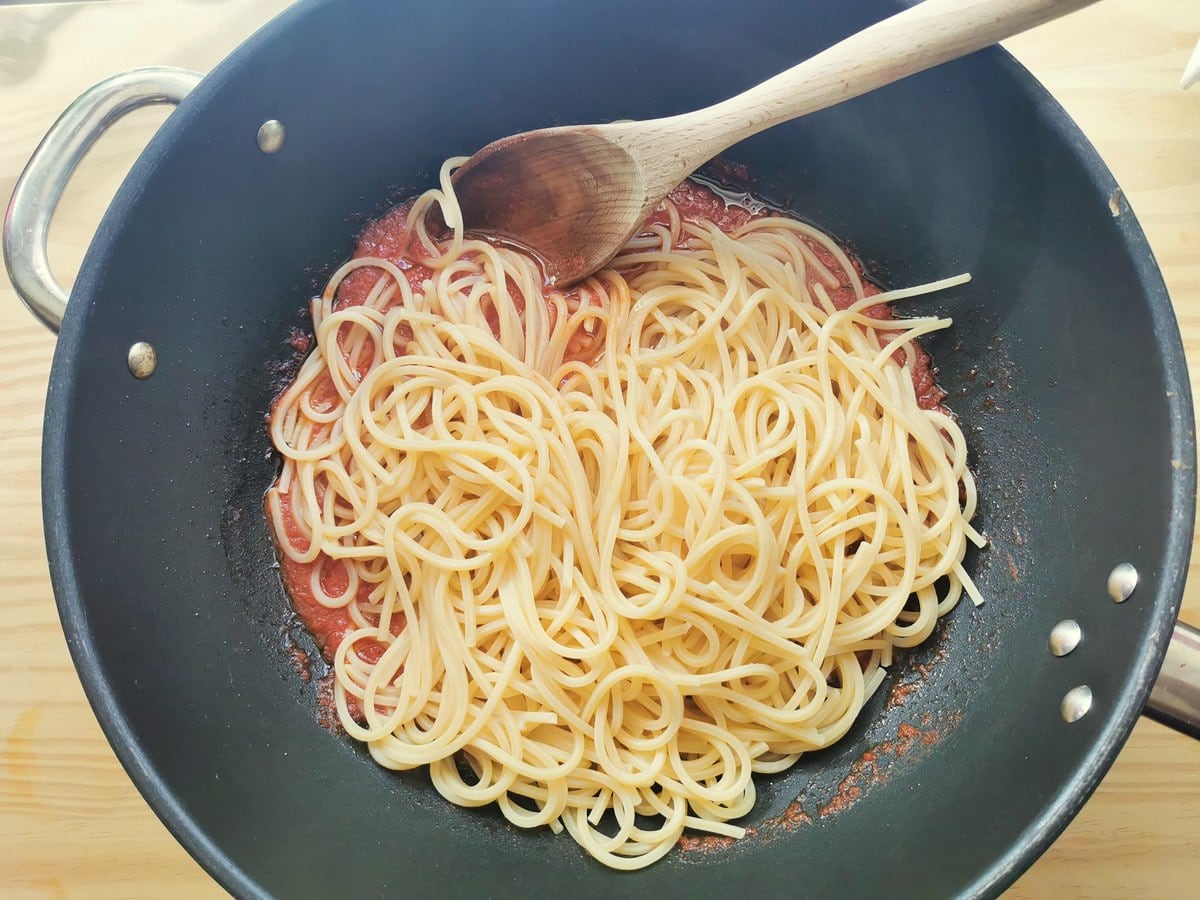 Cooked spaghetti alla chitarra in deep skillet with tomato sauce.