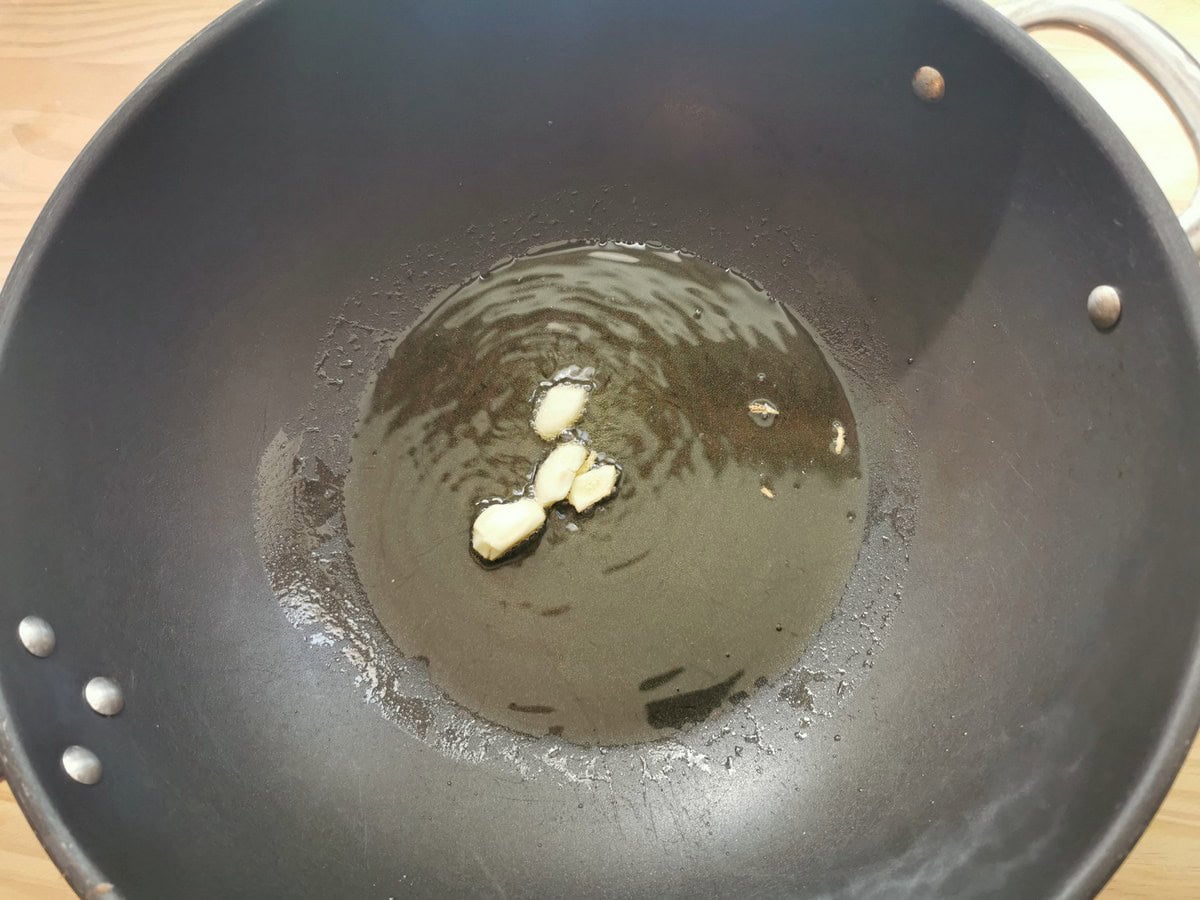 Garlic cloves frying in olive oil in deep skillet.