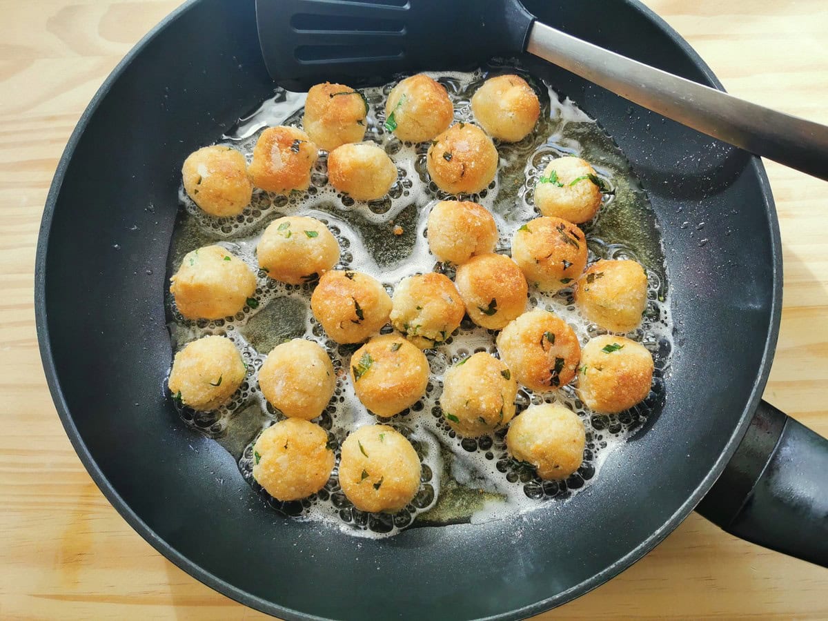 Pallotte cacio e ova cheese and egg balls frying in oil in frying pan.