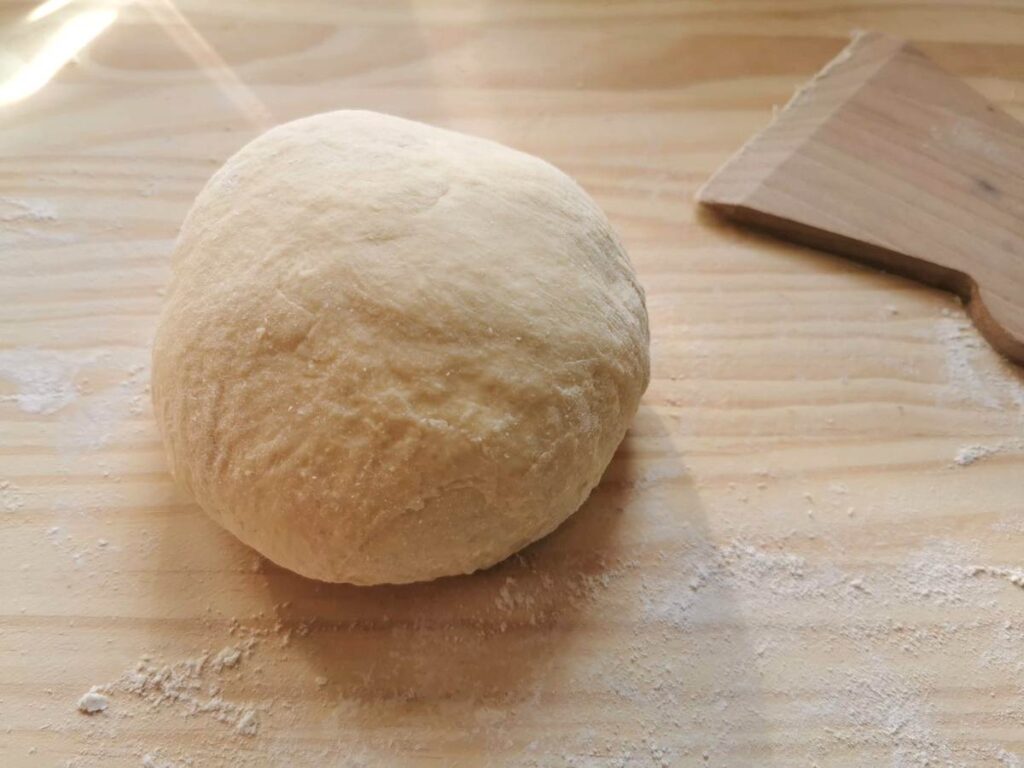 Ball of pansotti dough on wooden pastry board