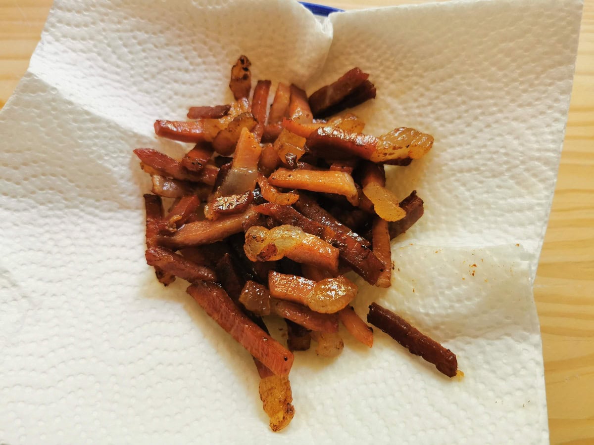 Fried culatello prosciutto on kitchen paper in a bowl.