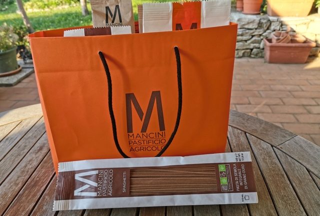 Pasta Mancini types of pasta in orange shopping bag on wooden table