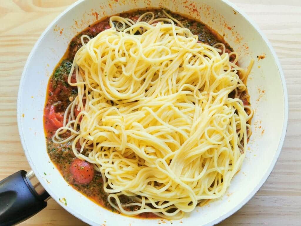 cooked tagliolini added to portofino sauce in pan