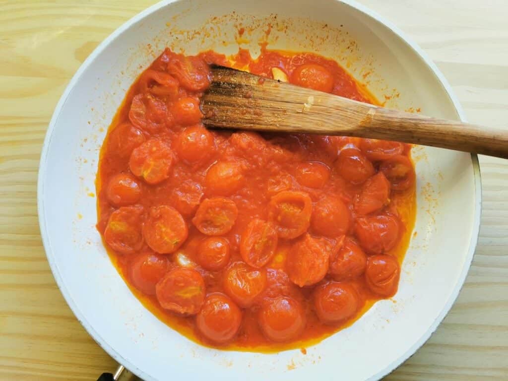 halved cherry tomatoes and tomato passata cooking in pan