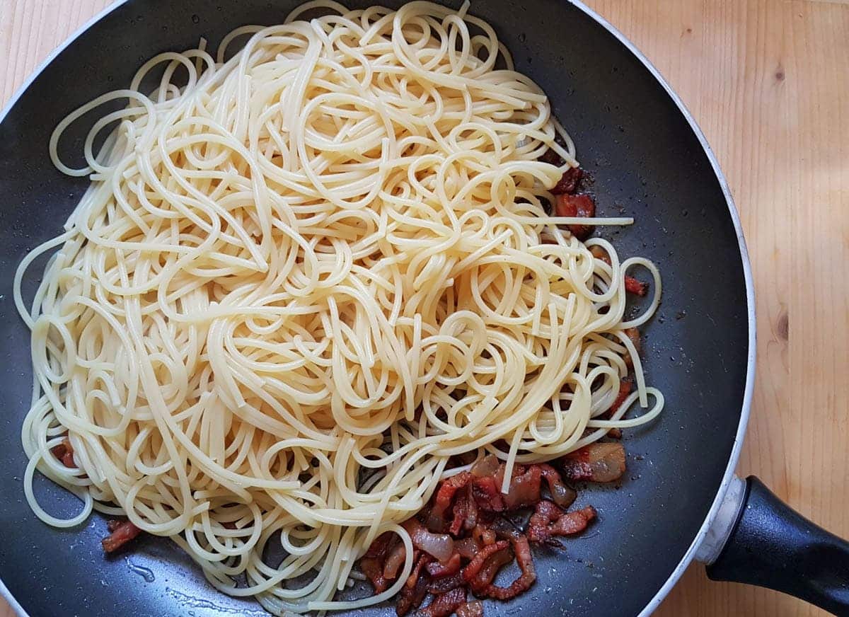 cooked spaghetti and guanciale in frying pan