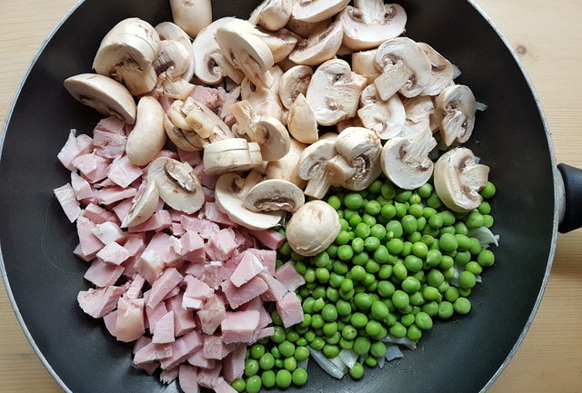 shelled peas, sliced mushrooms, cooked ham pieces and chopped onion in deep frying pan