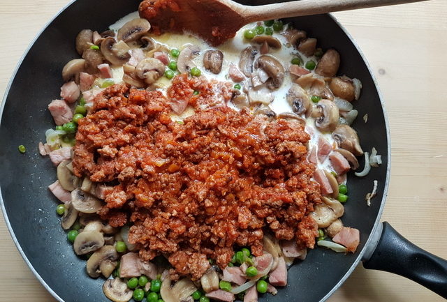 Bolognese sauce and cream added to mushroom, ham and pea sauce in deep frying pan