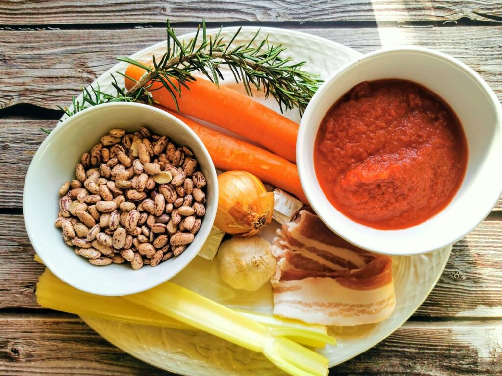 Ingredients for pasta with beans on white plate