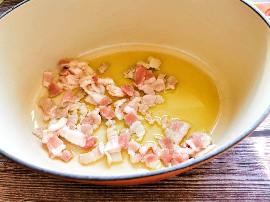 Pieces of pancetta with olive oil in Dutch oven