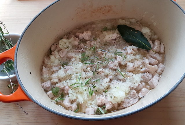 pork tenderloin pieces, onions and herbs cooking in dutch oven