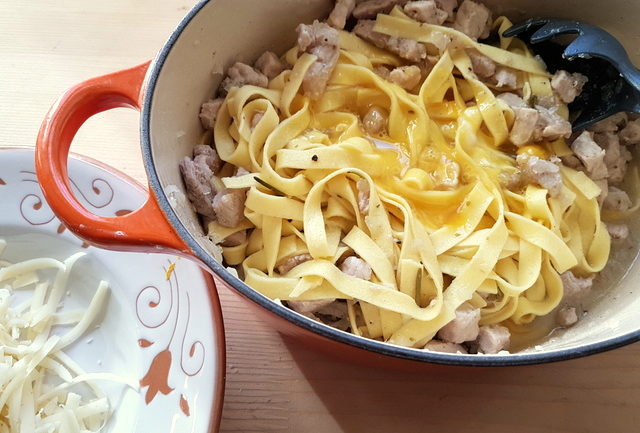 Tagliatelle pasta with cinnamon spiced pork ragu and raw eggs in Dutch oven