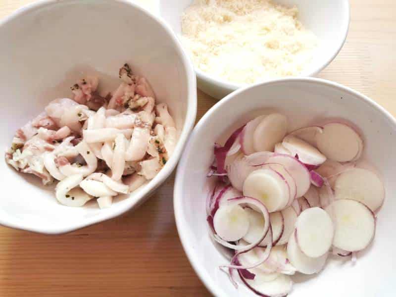 sliced Tropea onions and pieces of lardo in white bowls.