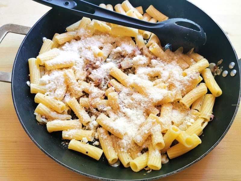 grated pecorino added to pasta, onions and lardo in skillet