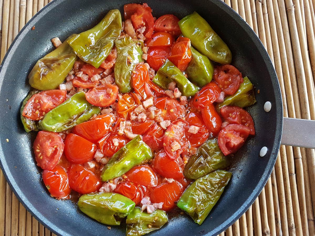 Adding pancetta to the friggitelli pepper and tomatoes