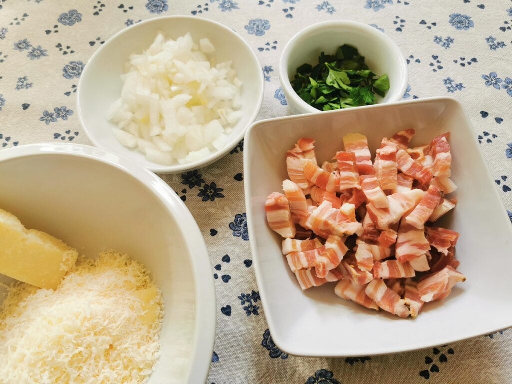 Cut pancetta in white bowl, grated pecorino in white bowl and peeled and chopped onion in white bowl