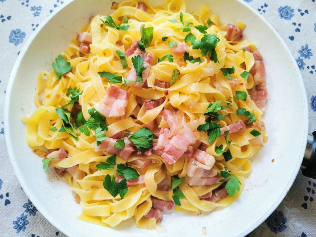 Fresh parsley and basil added to pan with pasta and pancetta