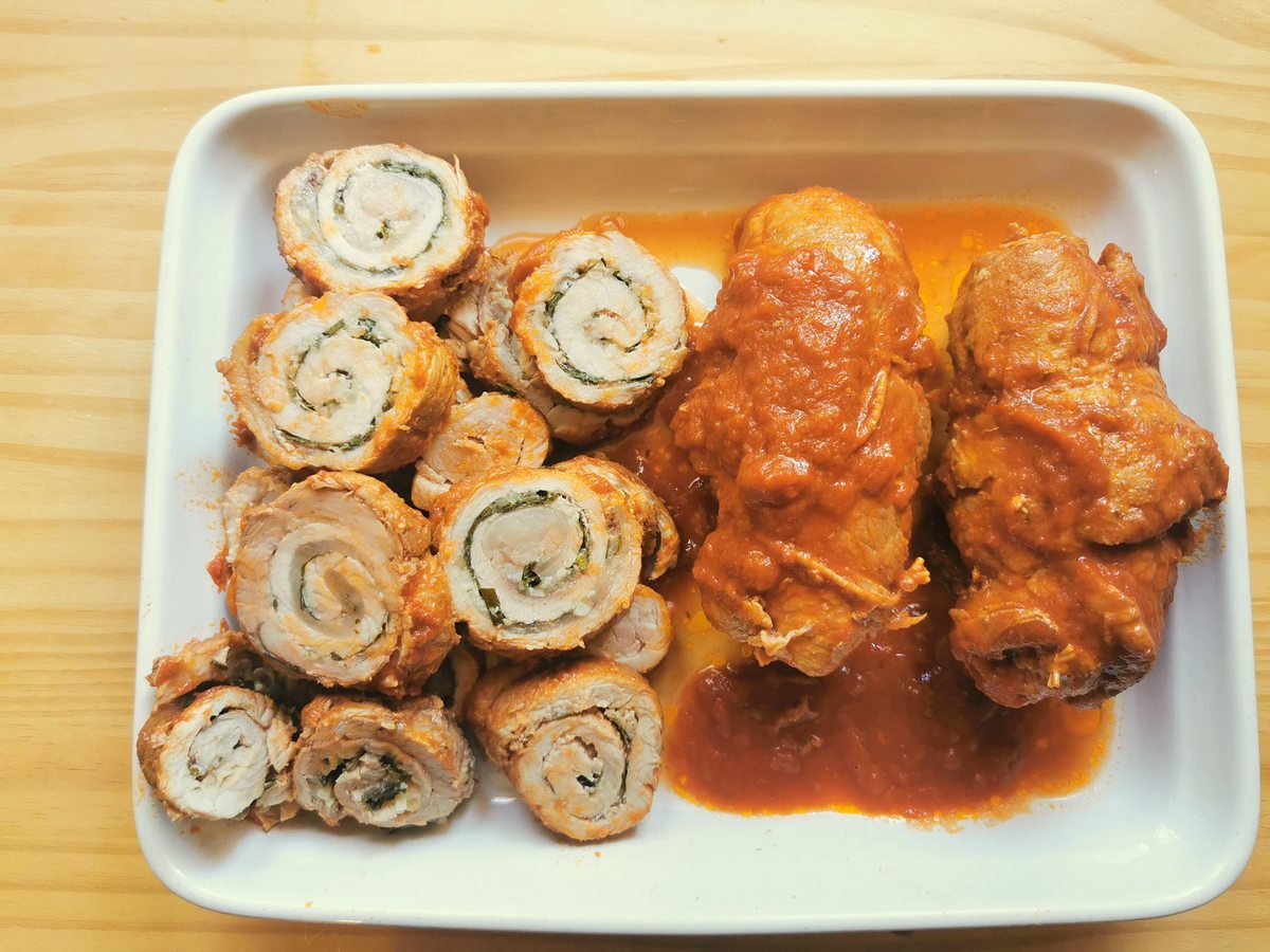 Two whole pork involtini and two sliced pork involtini on white plate.