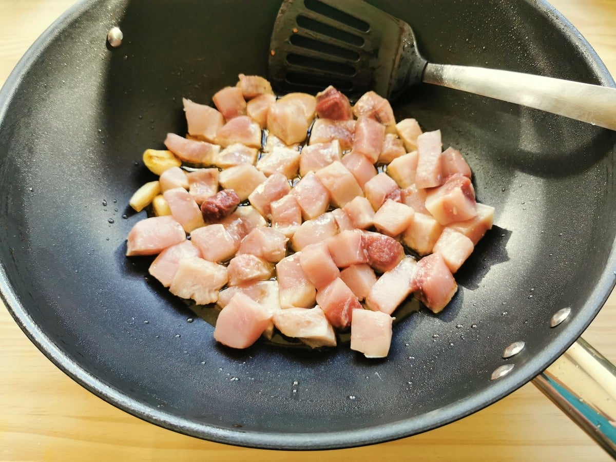 Garlic and swordfish cooking in a pan.