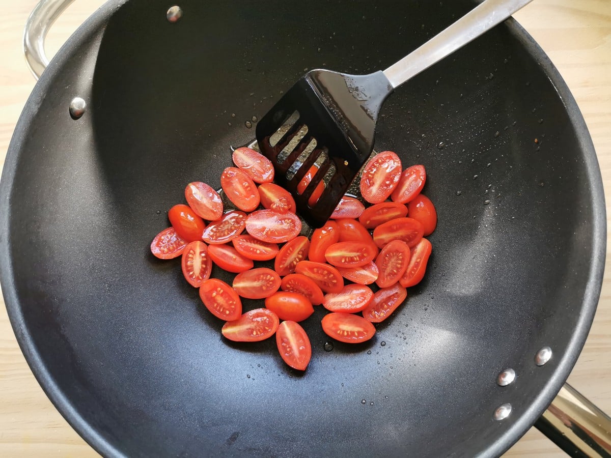 Cherry tomatoes cooking in a pan.