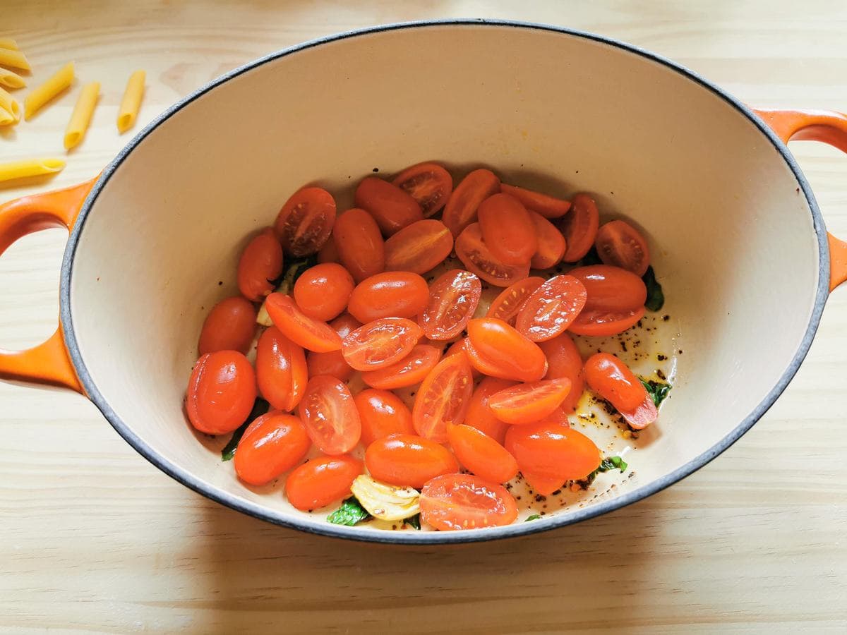 small tomato halves in Dutch oven with garlic, basil and peperocino flakes