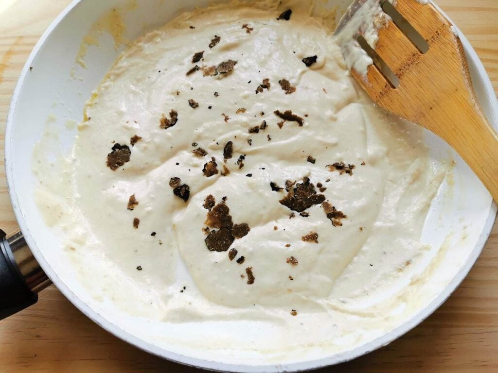 mascarpone cream in frying pan with small pieces of truffle in it.