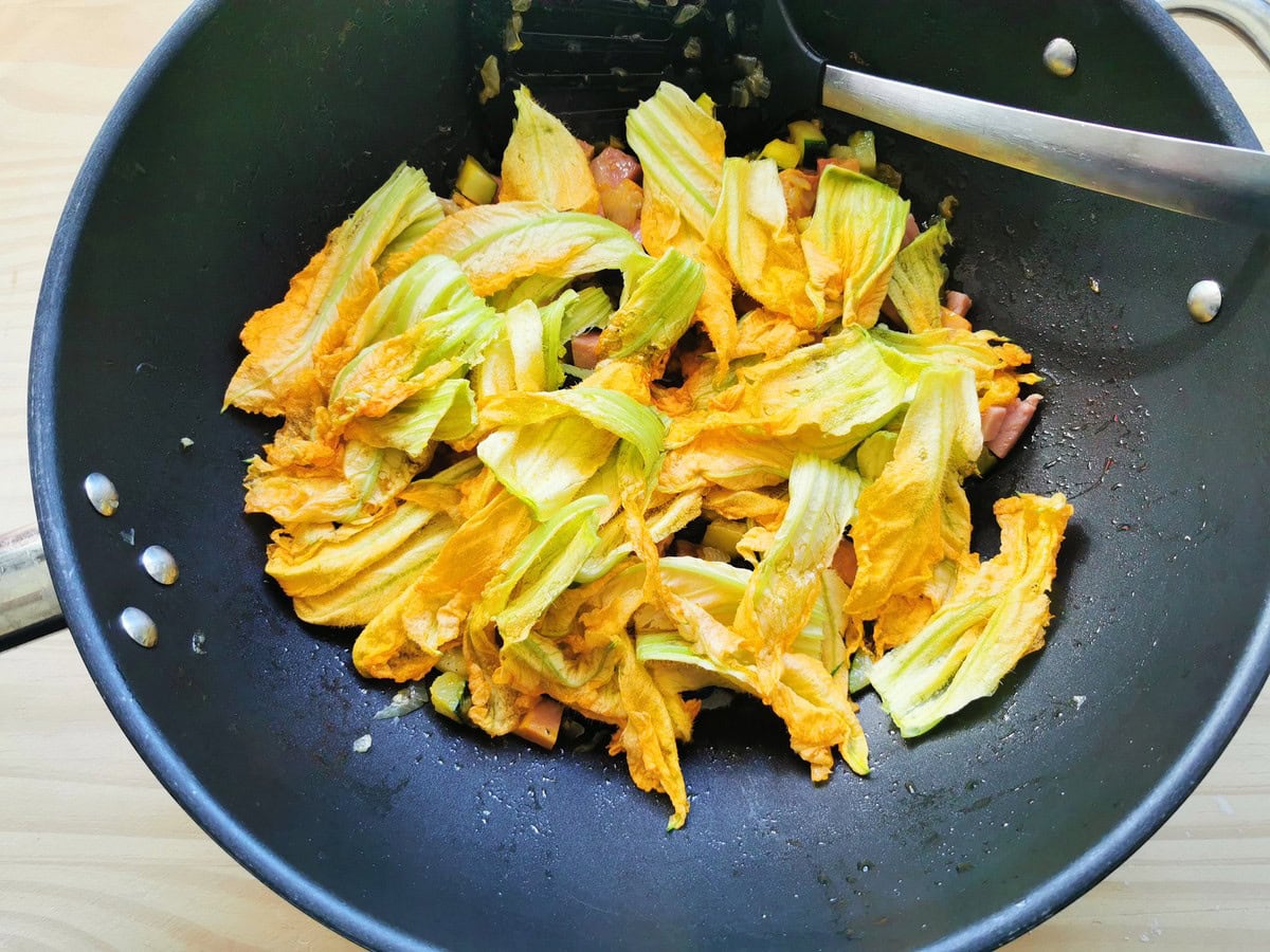 Cut zucchini flowers added to skillet with pasta sauce.
