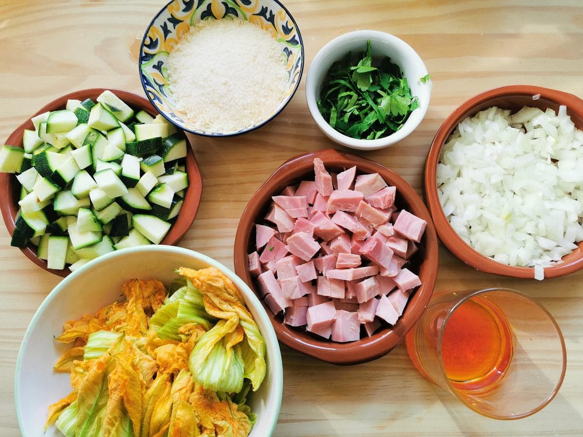 Prepare ingredients in separate bowls; chopped ham, chopped onion, cut zucchini flowers, cubed zucchini, chopped parsley and saffron in water.