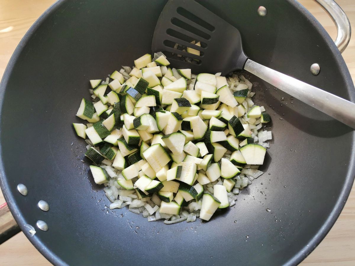 Chopped onion and cubed zucchini cooking in deep skillet.